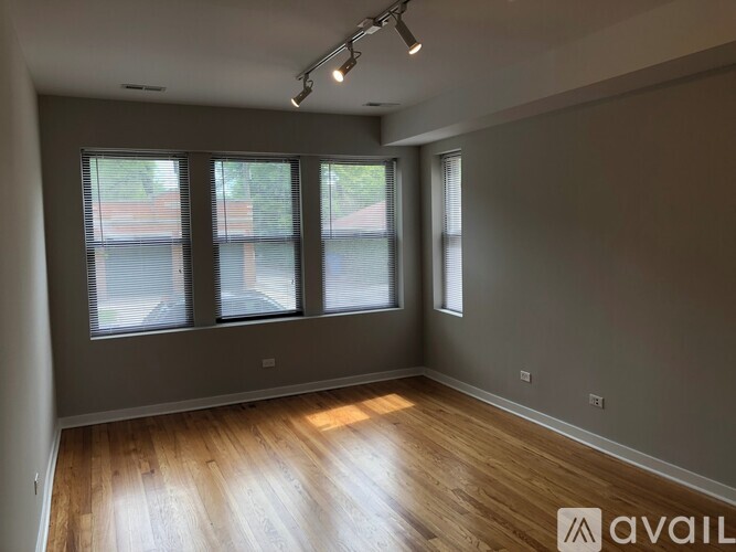 A room with wooden floors and three windows.
