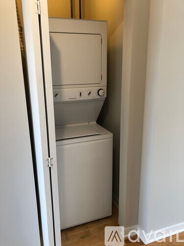A white dishwasher is in a narrow space between a wall and a door.