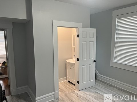 A white door with a black handle is open in a room with light grey walls.