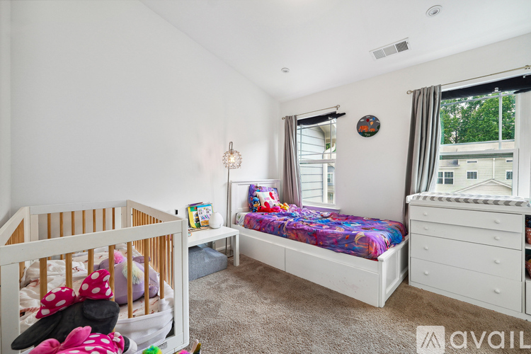 A bedroom with a white crib and a bed with a colorful bedspread.