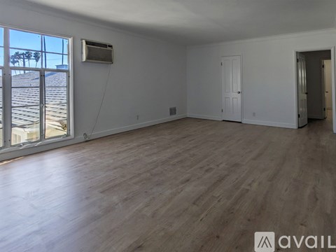 A spacious room with wooden flooring and white walls.