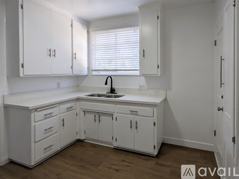 A kitchen with white cabinets and a sink.