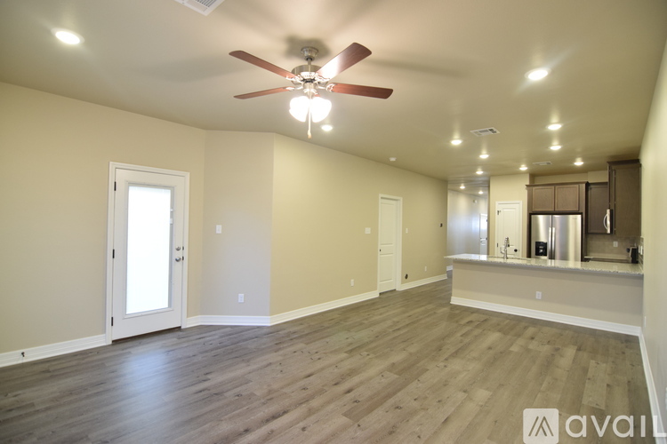A spacious room with a ceiling fan and hardwood flooring.