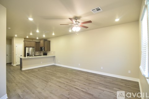 A spacious room with a ceiling fan and lighting fixtures.