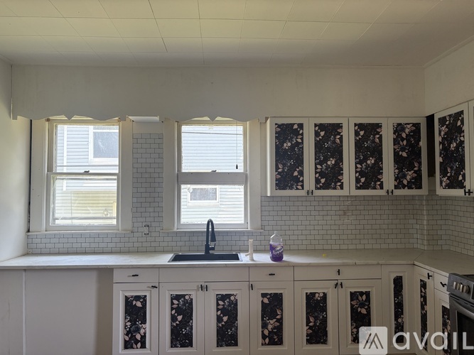 A kitchen with white cabinets and a black and white tiled backsplash.
