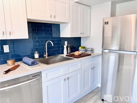 A kitchen with white cabinets and a blue backsplash.