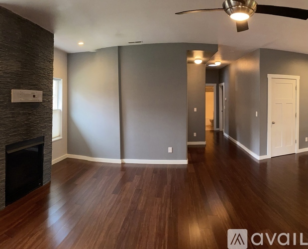 A spacious room with a fireplace and wood flooring.