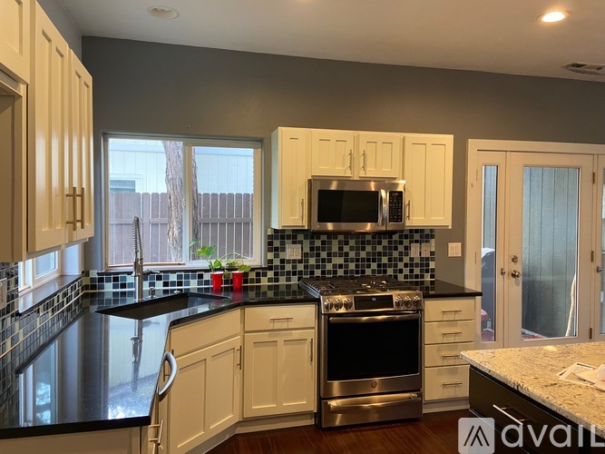 A kitchen with white cabinets and black countertops.