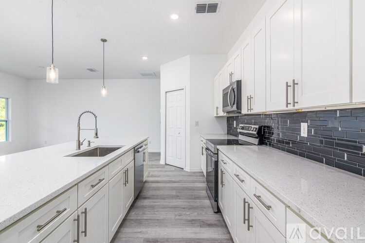 A kitchen with white cabinets and a black counter.