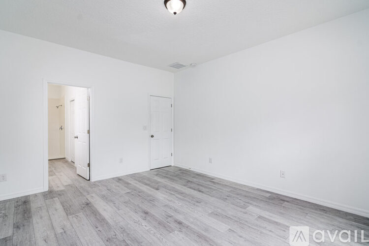 A spacious room with wood flooring and white walls.