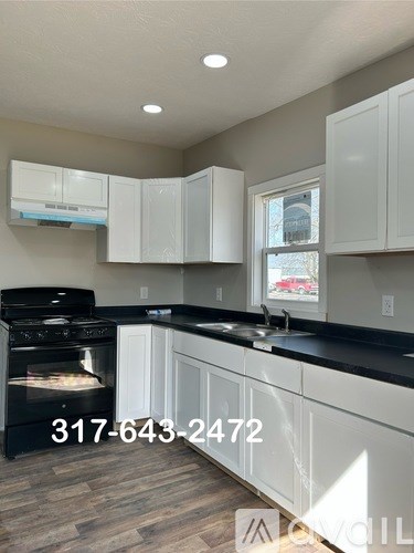 A kitchen with white cabinets and a black stove top oven.