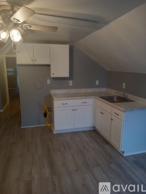 A kitchen with white cabinets and a wooden floor.