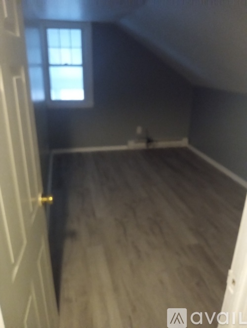 A room with a window and wooden flooring.