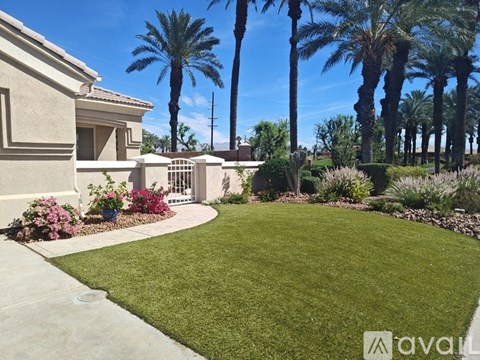 A house with a well-manicured lawn and palm trees in the background.