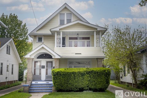 A two-story house with a front yard and a hedge.