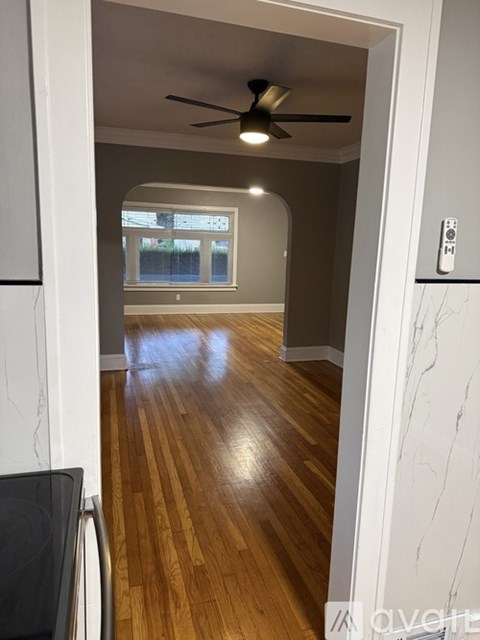 A room with a ceiling fan and wooden floors.