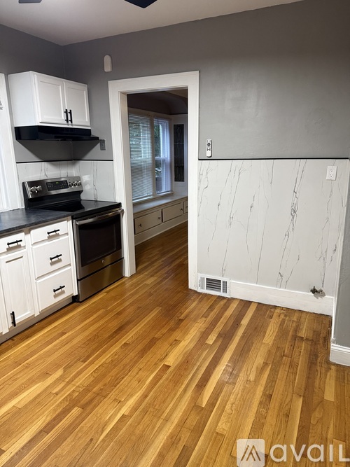 A kitchen with wooden floors and white cabinets.