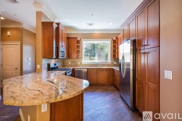 A kitchen with wooden cabinets and a marble island.