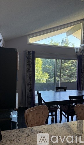 A dining room with a table and chairs and a window overlooking a tree.