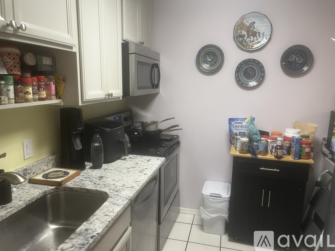 A kitchen with a sink, microwave, and a few plates on the wall.
