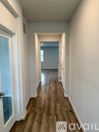 A hallway with wooden floors and white walls leading to a blue door.