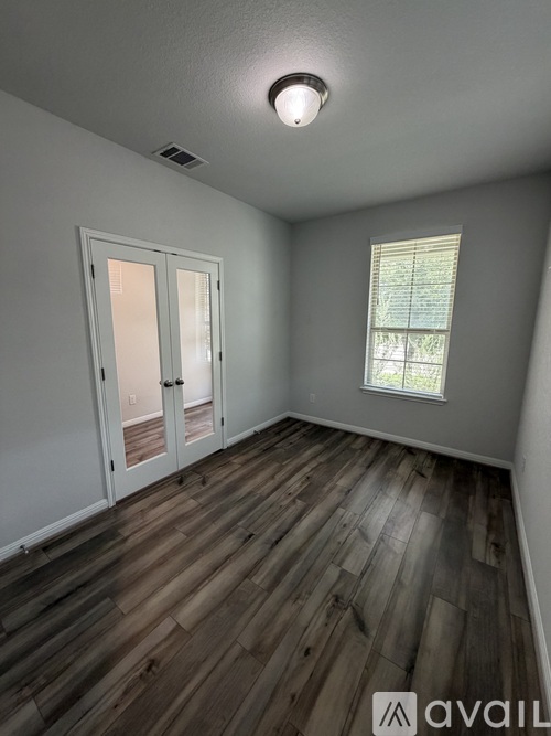 A room with wooden flooring and a window with blinds.