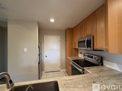 A kitchen with wooden cabinets and a stainless steel refrigerator.