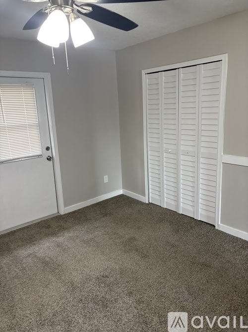 A room with a ceiling fan and a closed white door.