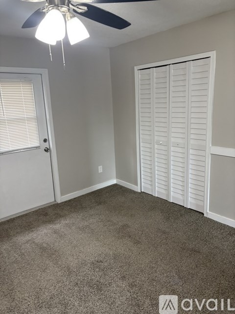 A room with a ceiling fan and a closed white door.
