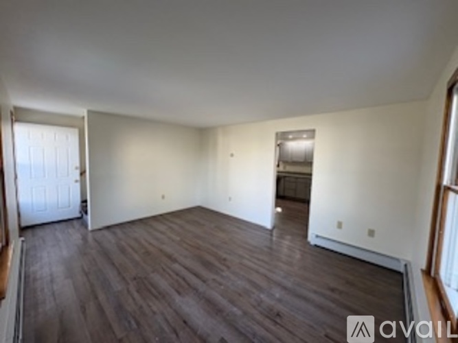 A spacious room with wood flooring and white walls.