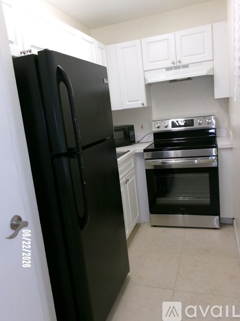 A black fridge in a kitchen with a stove top oven.