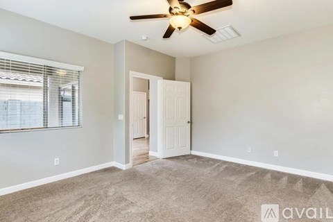 A room with a ceiling fan and a door leading to another room.