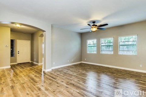 A spacious room with wood flooring and a ceiling fan.