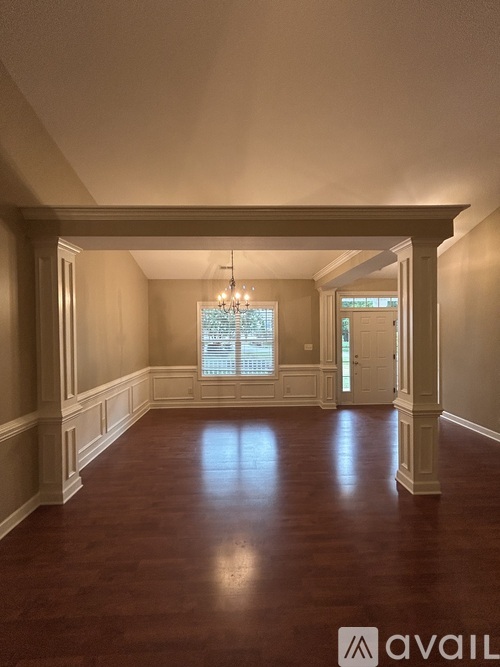 A large empty room with wooden floors and a chandelier.