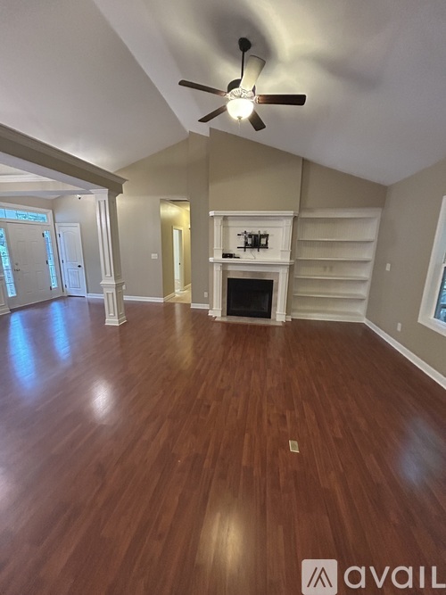 A spacious room with a fireplace and a ceiling fan.