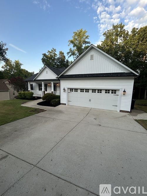 A white house with a black roof and a garage door.