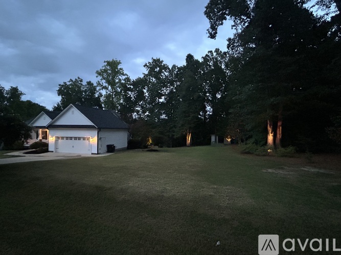 A house with a white garage is surrounded by trees.