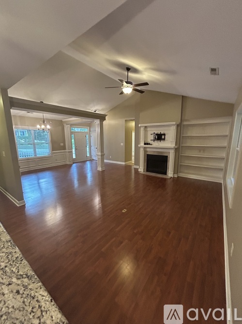 A living room with wood flooring and a ceiling fan.