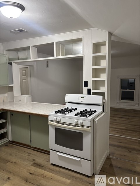 A white stove is in a kitchen with green cabinets.