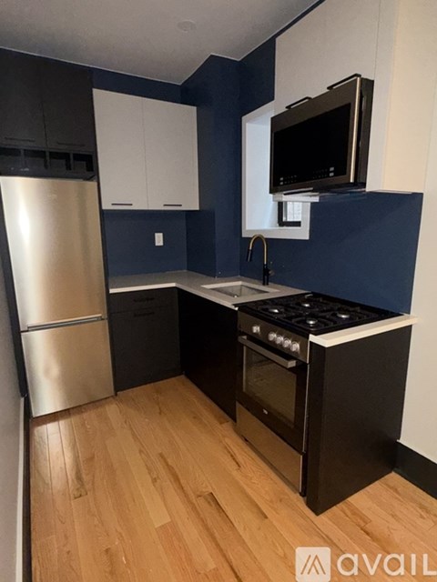 A kitchen with a stainless steel refrigerator, black cabinets, and a black stove top oven.