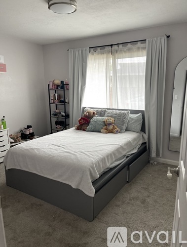 A bedroom with a bed, a nightstand, and a window with curtains.