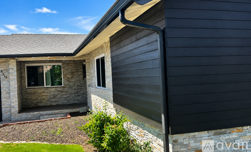 A house with a grey exterior and a stone wall.