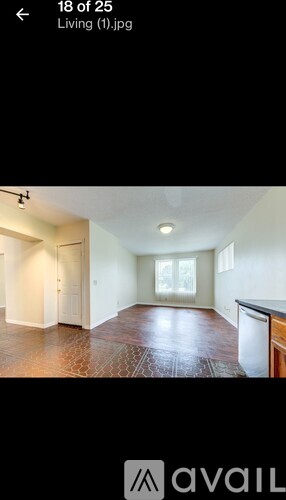 A living room with a brown floor and white walls.