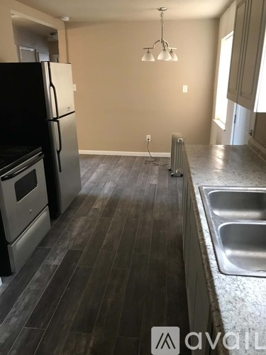 A kitchen with a black fridge, stove, and sink.