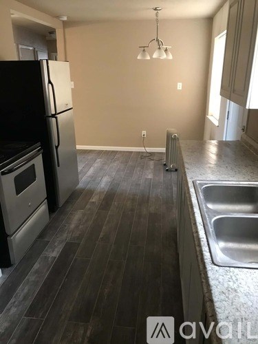 A kitchen with a black fridge, stove, and sink.