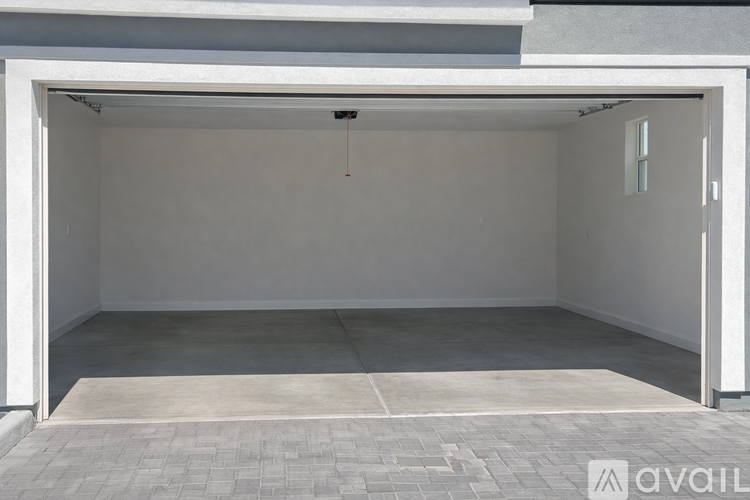 A large white garage door is open, revealing a spacious interior.