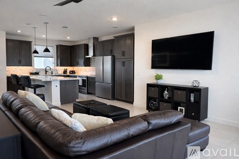 A modern living room with a brown leather couch and a flat screen TV mounted on the wall.
