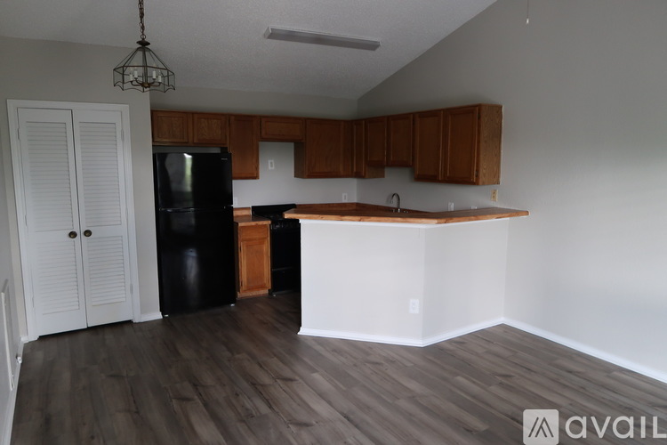 A kitchen with wooden cabinets and a black fridge.