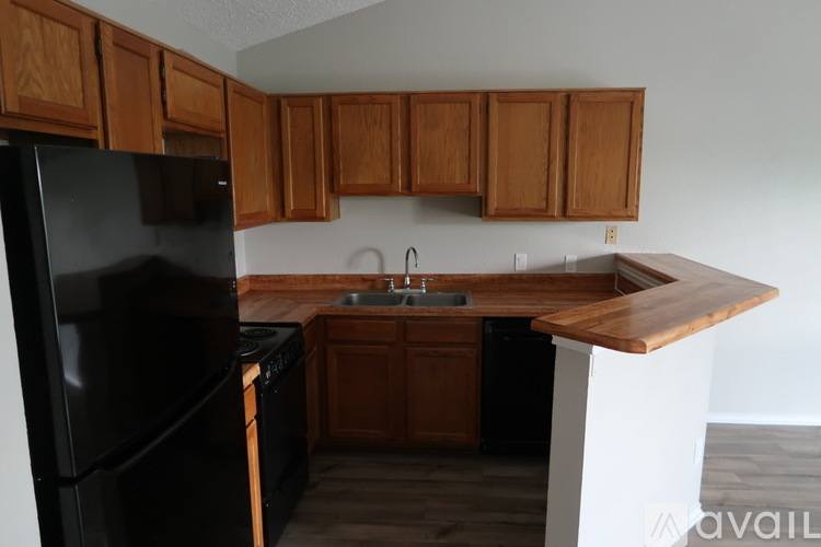 A kitchen with wooden cabinets and a black refrigerator.
