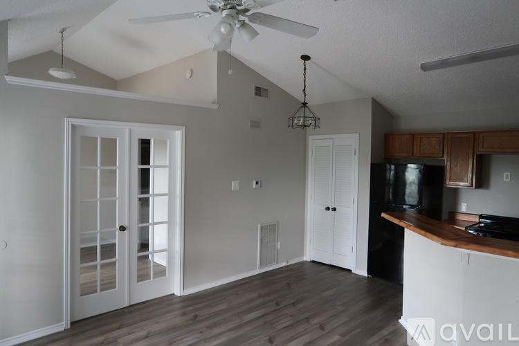 A kitchen with a black fridge and wooden cabinets.